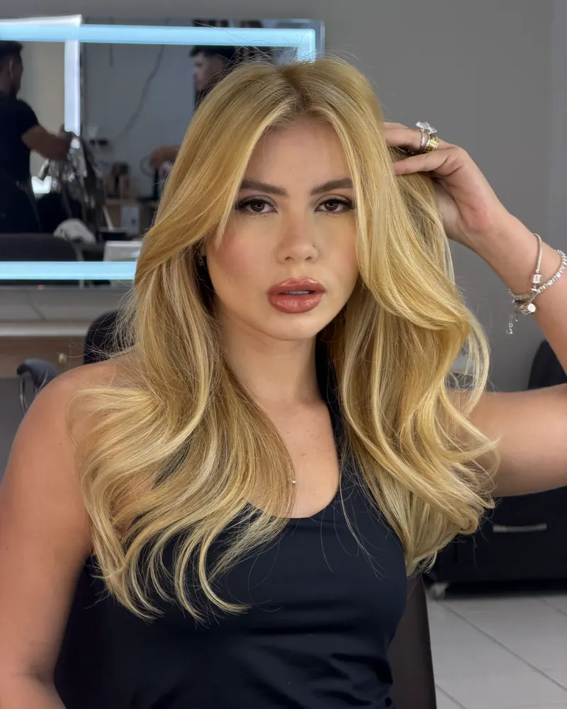 Bell de cabelo loiro em um salão, com a mão no cabelo