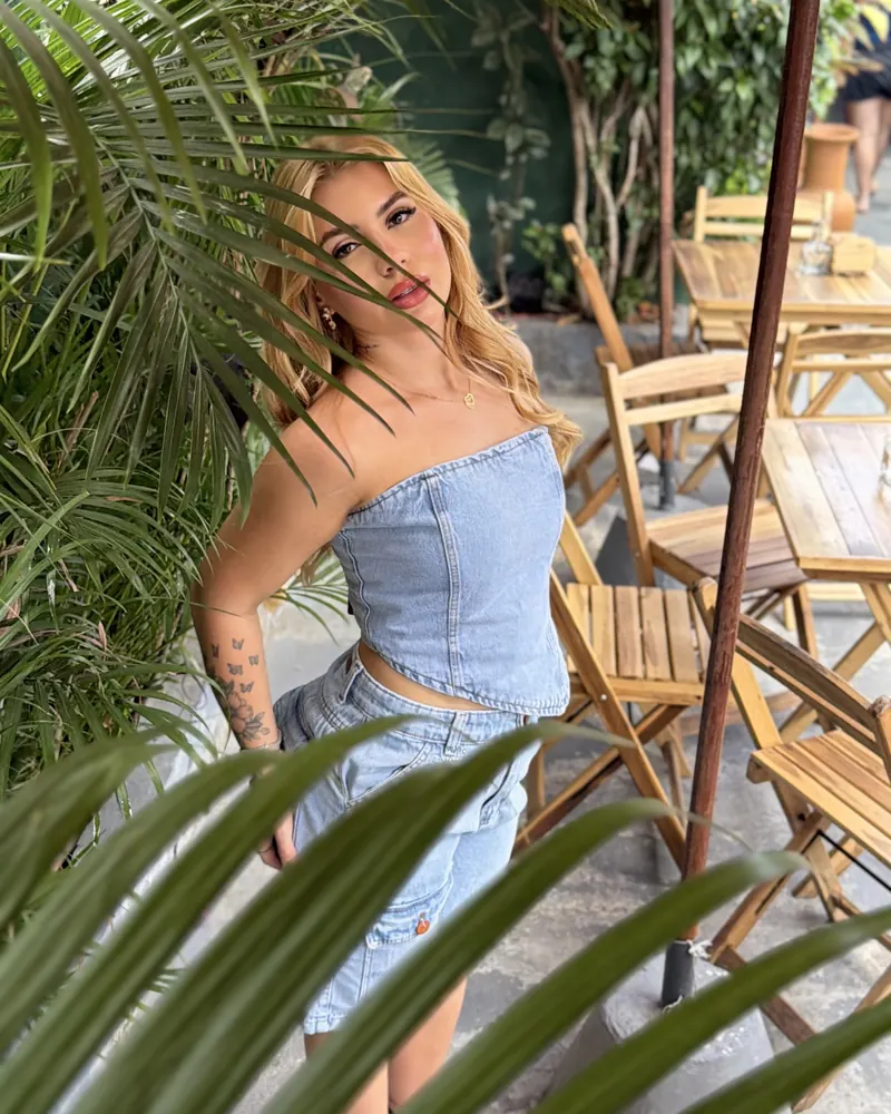 Bell de top jeans, olhando de lado entre as folhagens